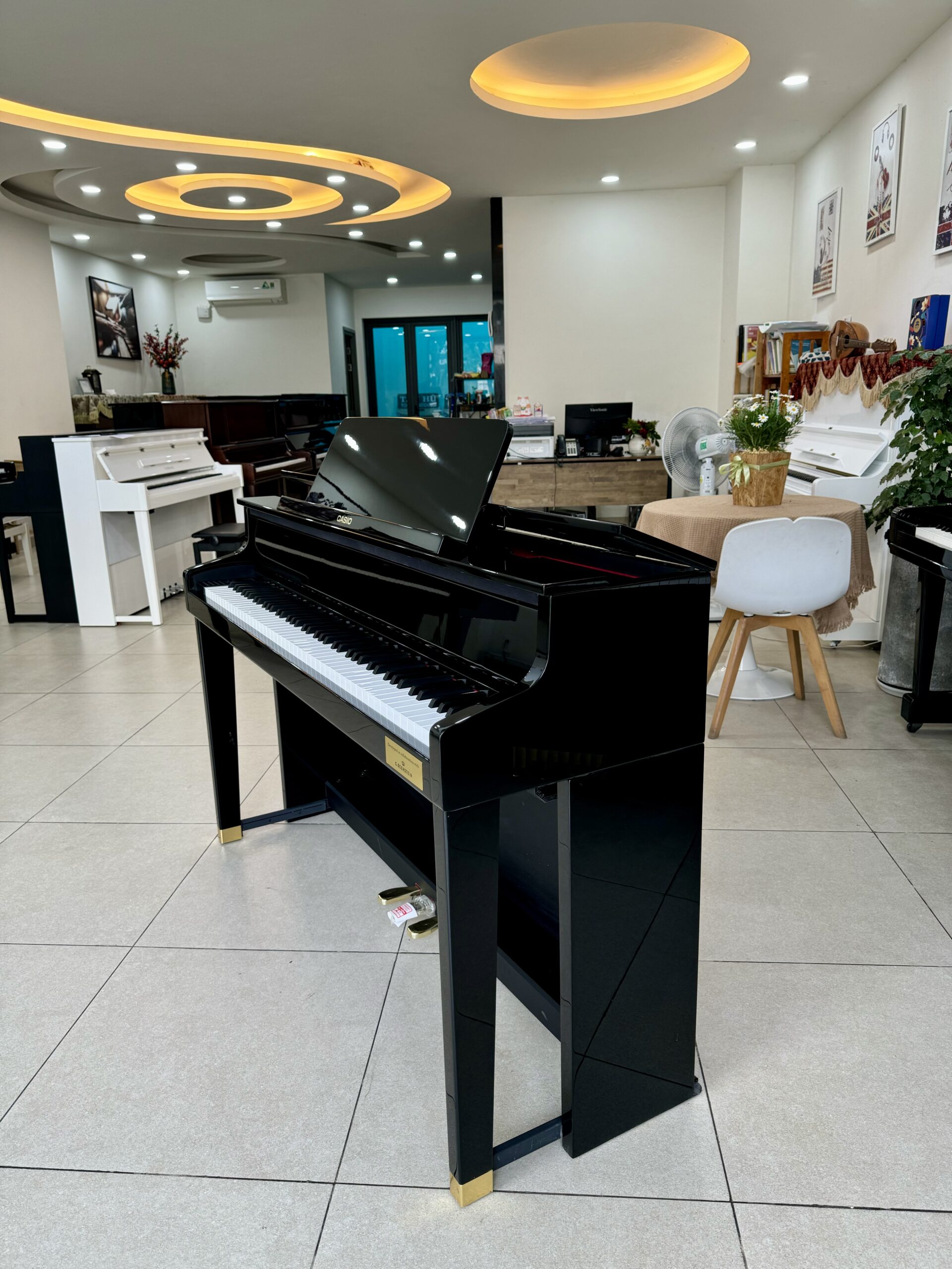 hình ảnh chụp nghiêng đàn piano điện Casio GP-1000 PE tại cửa hàng piano Vạn Phúc Music. Xung quanh là các cây đàn khác tại cửa hàng