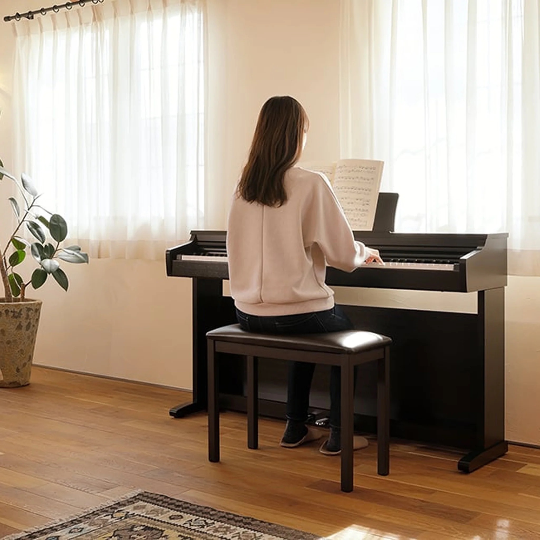 hình ảnh một cô gái đang ngồi chơi đàn piano Kawai KDP-120 B tại nhà