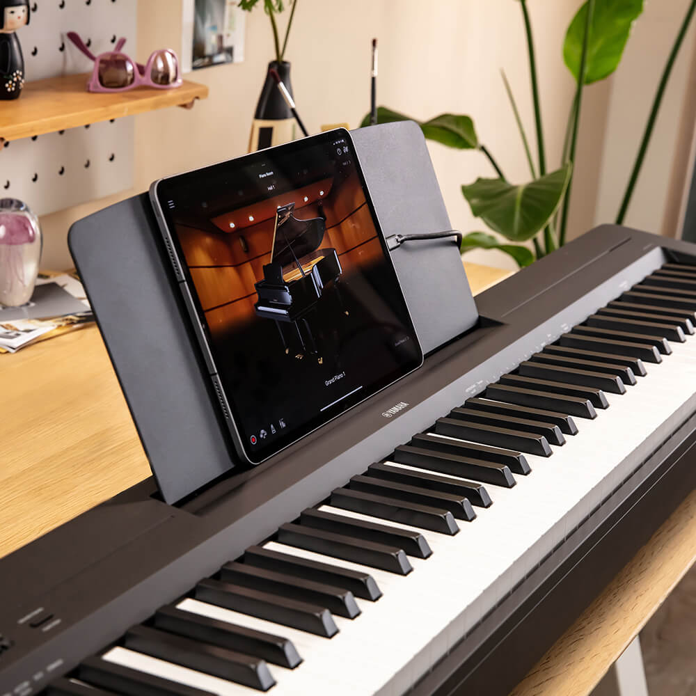 Yamaha P-145 và máy tính bảng Đàn piano điện Yamaha P-145 màu đen, phù hợp cho người mới học hoặc luyện tập tại nhà, với máy tính bảng trên giá nhạc