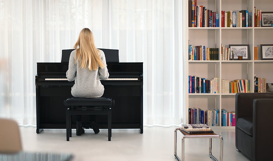 hình ảnh cô gái đang ngồi chơi đàn Kawai CA701 B trong một căn phòng hiện đại