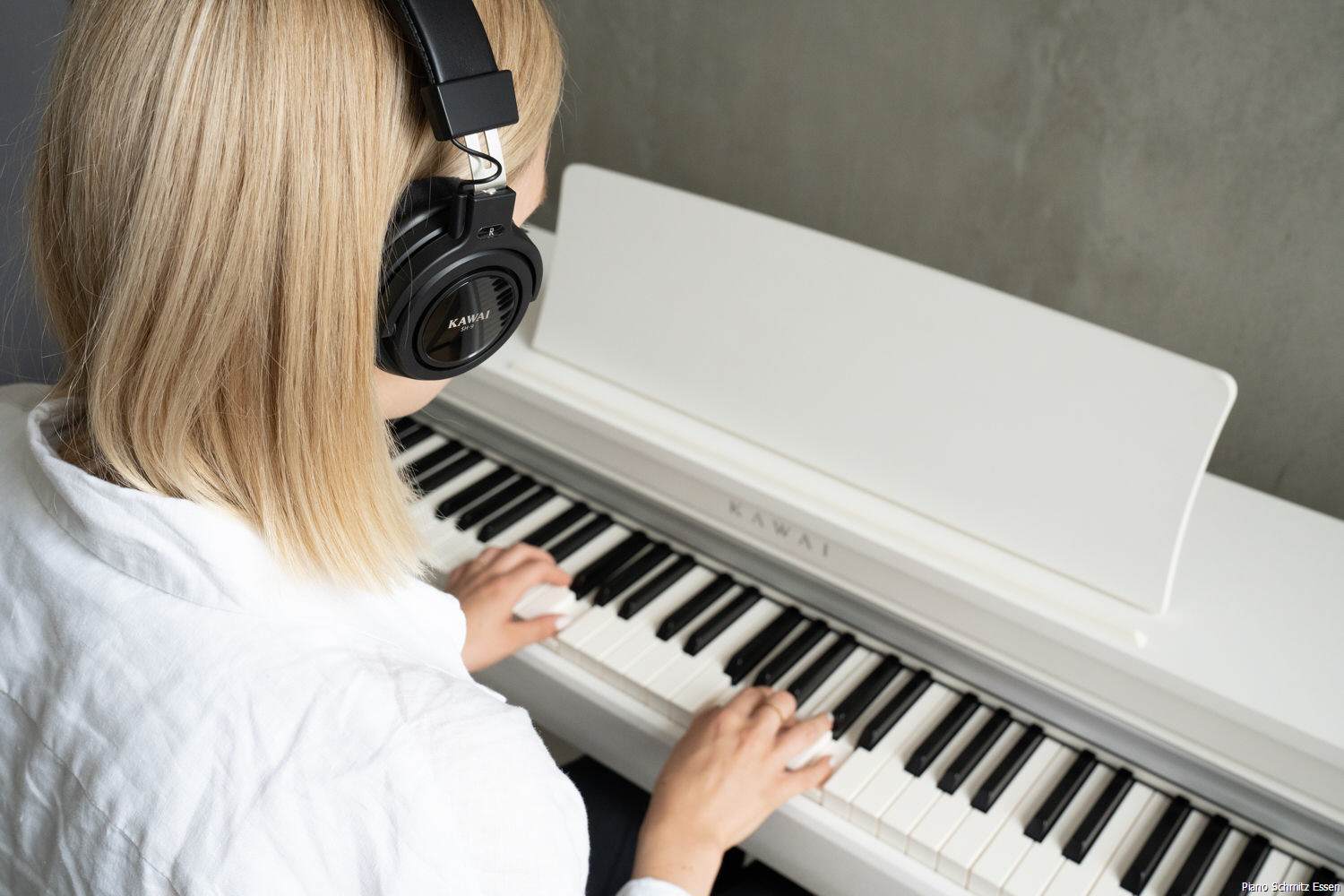 hình ảnh một bé gái đang đeo tai nghe ba chiều sử dụng công nghệ Spatial Headphone Sound (SHS) của đàn piano Kawai CN 301 WH