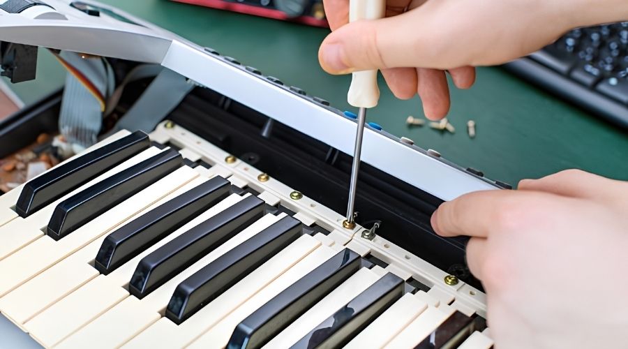 Dùng tua vít tháo nắp đàn, kiểm tra phím kẹt